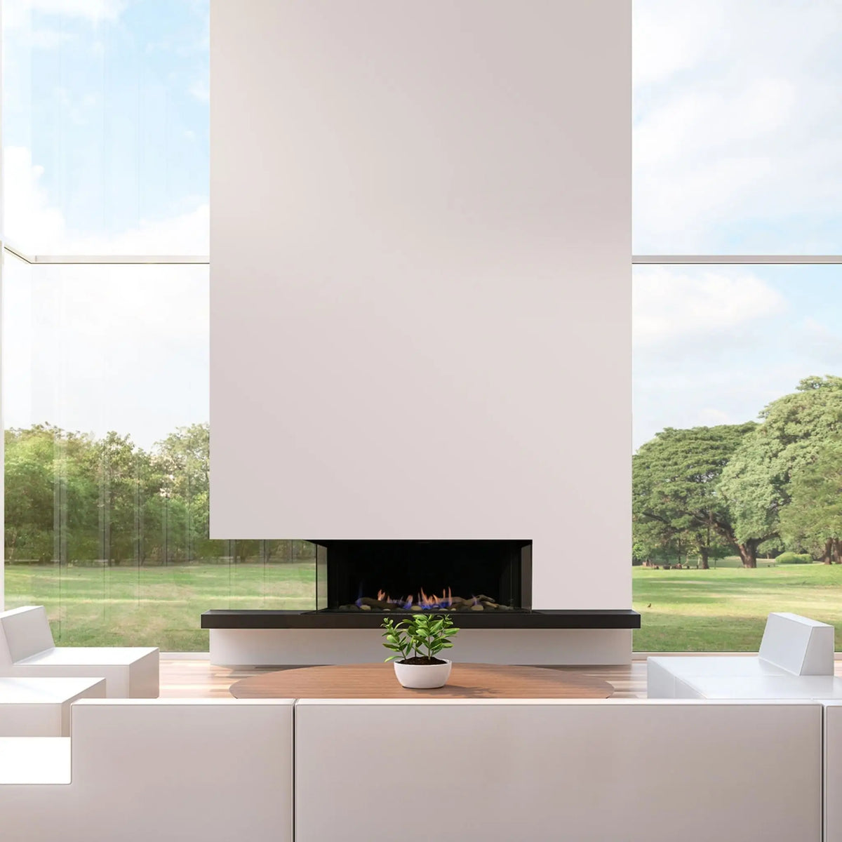 A modern linear fireplace with a tall white chimney stack, set into a minimalist white outdoor patio with a small potted plant in the foreground and a grassy park visible through large windows.