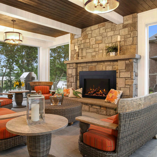 Outdoor patio with stone fireplace, wicker furniture, and orange cushions.