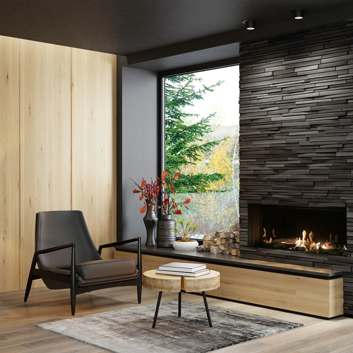 A modern living room interior featuring a black leather armchair, a round wooden coffee table, a gray rug, a built-in wood-burning fireplace with a dark stacked stone surround, and a large window looking out onto trees.
