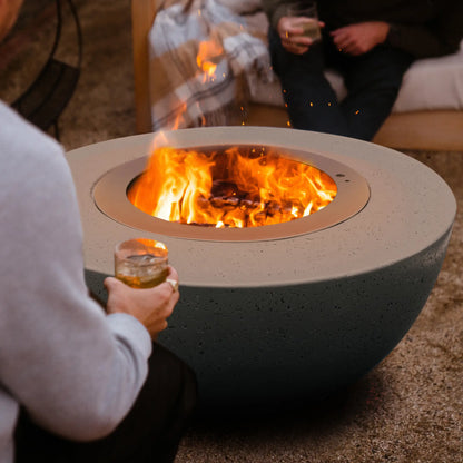 Close-up of a LUME Surround 1 Slate GFRC fire bowl with stainless steel smokeless insert and burning wood fire