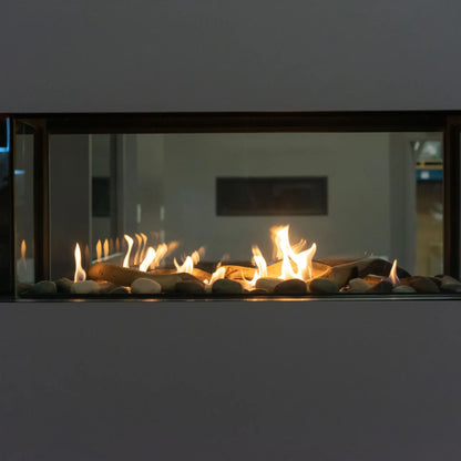 A modern linear fireplace insert with a dark wood frame, featuring glowing orange and yellow flames over dark stones and pebbles inside a glass front enclosure.