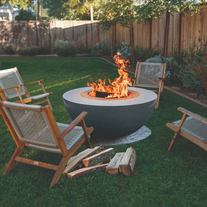 LUME Surround 1 smokeless wood-burning fire pit in a backyard with outdoor chairs and stacked firewood