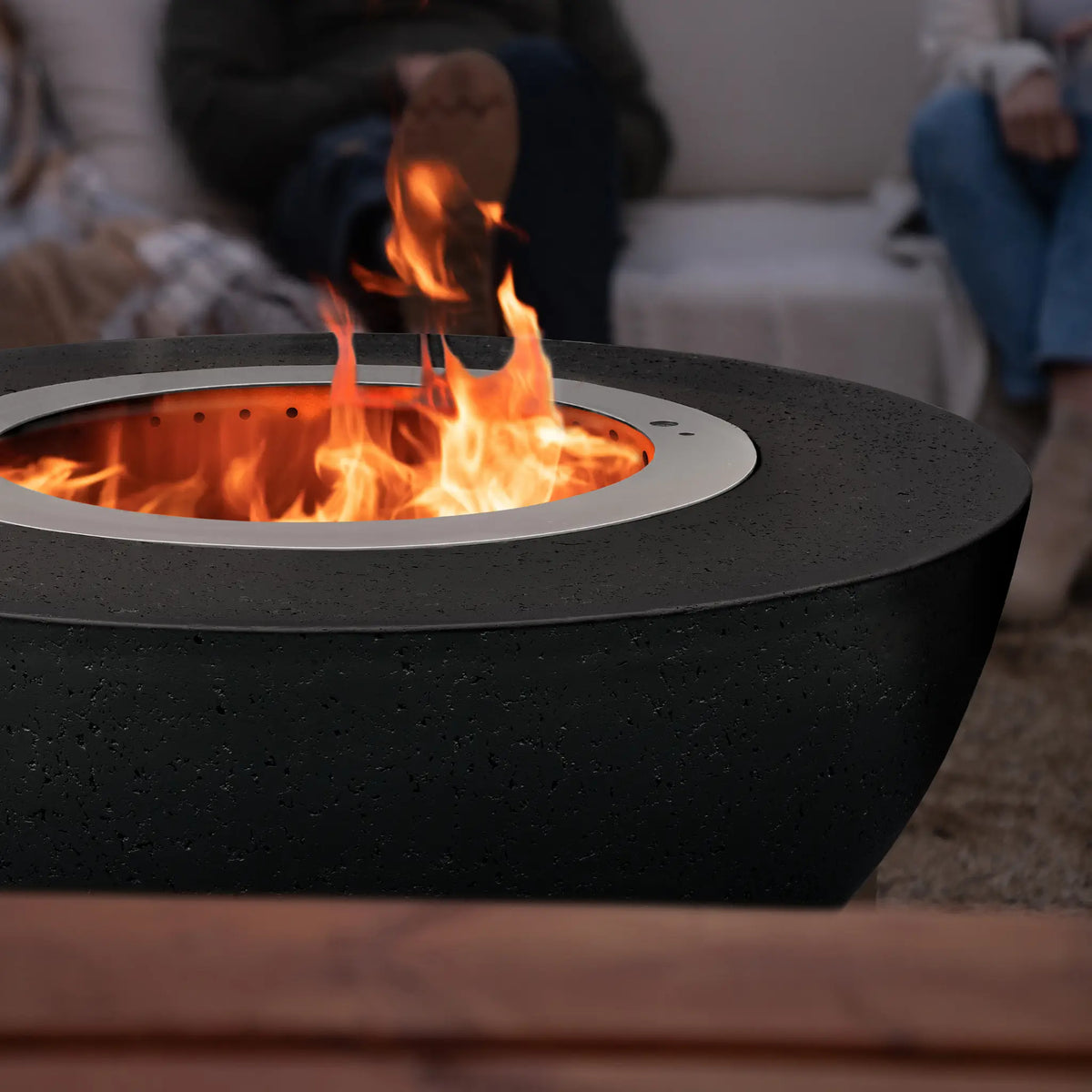 LUME Surround 1 Raven black GFRC smokeless fire pit with flames rising from the stainless steel insert