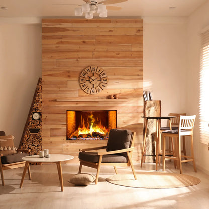 A built-in electric fireplace with orange flames set into a light wood plank wall below a round wooden clock, beside a triangular firewood rack, in a sunlit Scandinavian-style room with a wood dining table and bar stools.